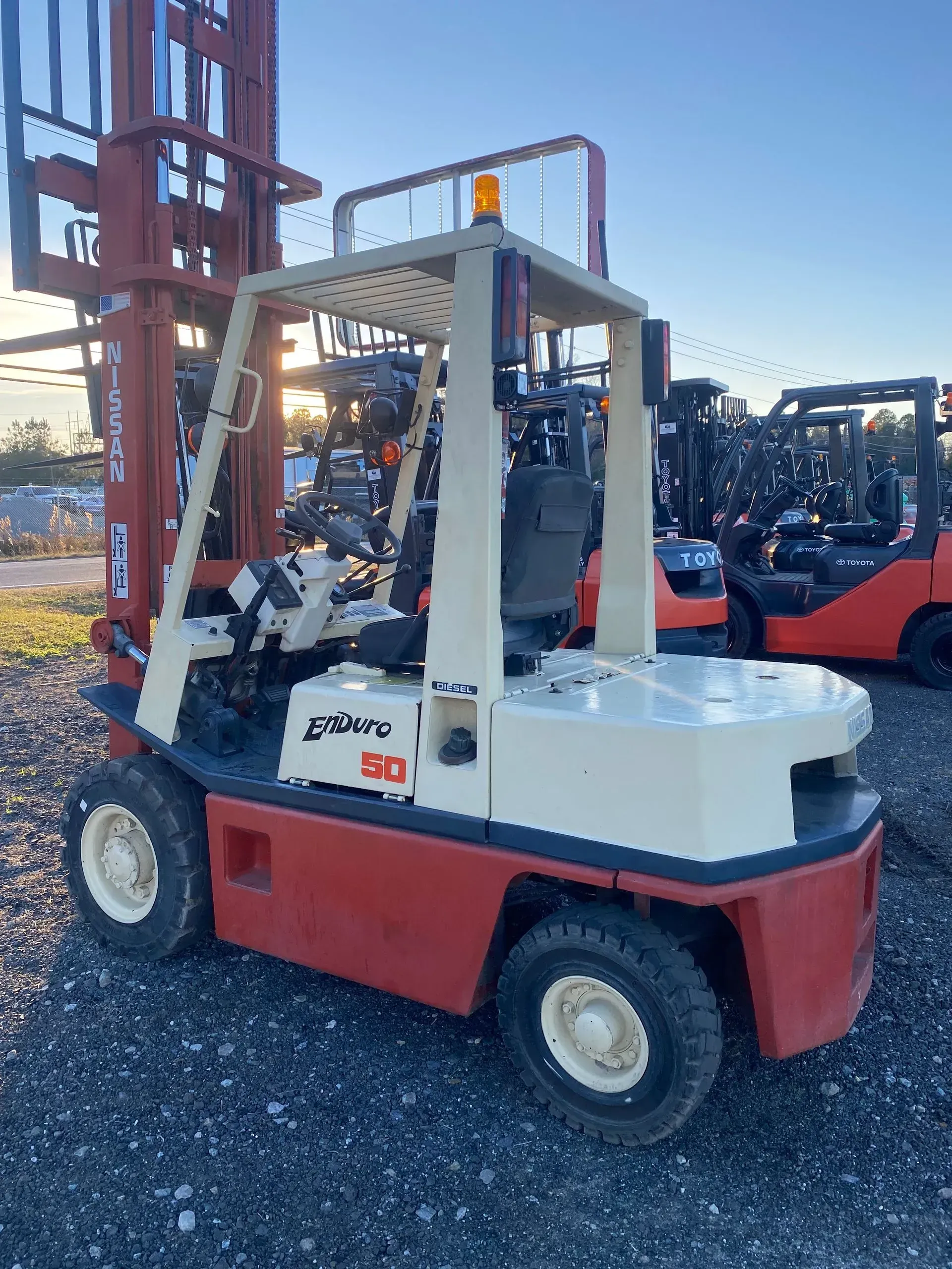 Red and cream forklift outdoors with another forklift in the background.