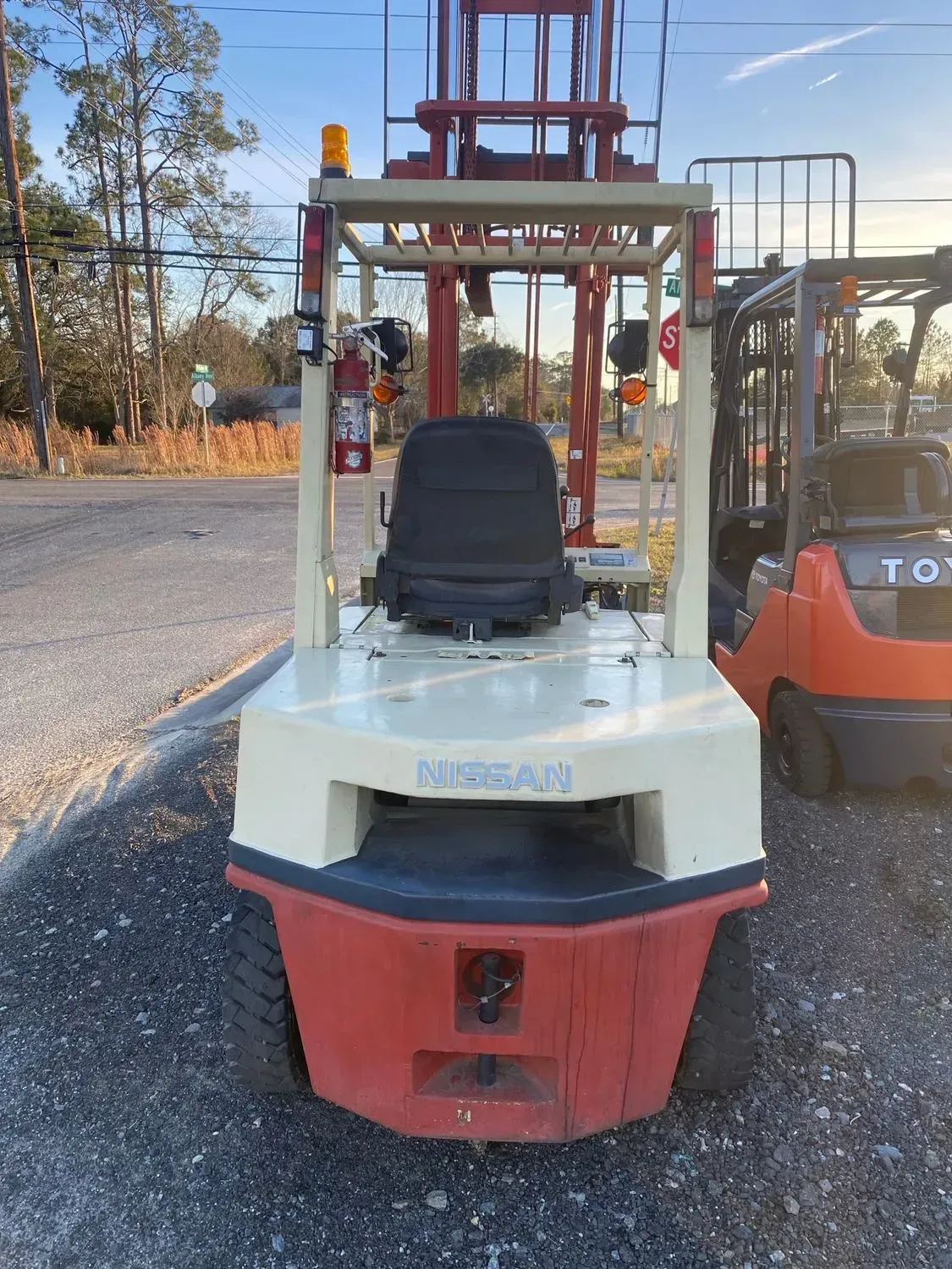 Nissan forklift, cream and red, parked outdoors. Another forklift is in the background.