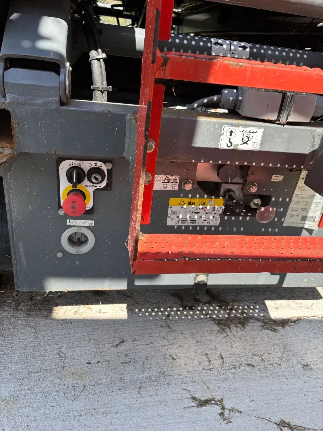 Control panel with red emergency stop button on an aerial lift.