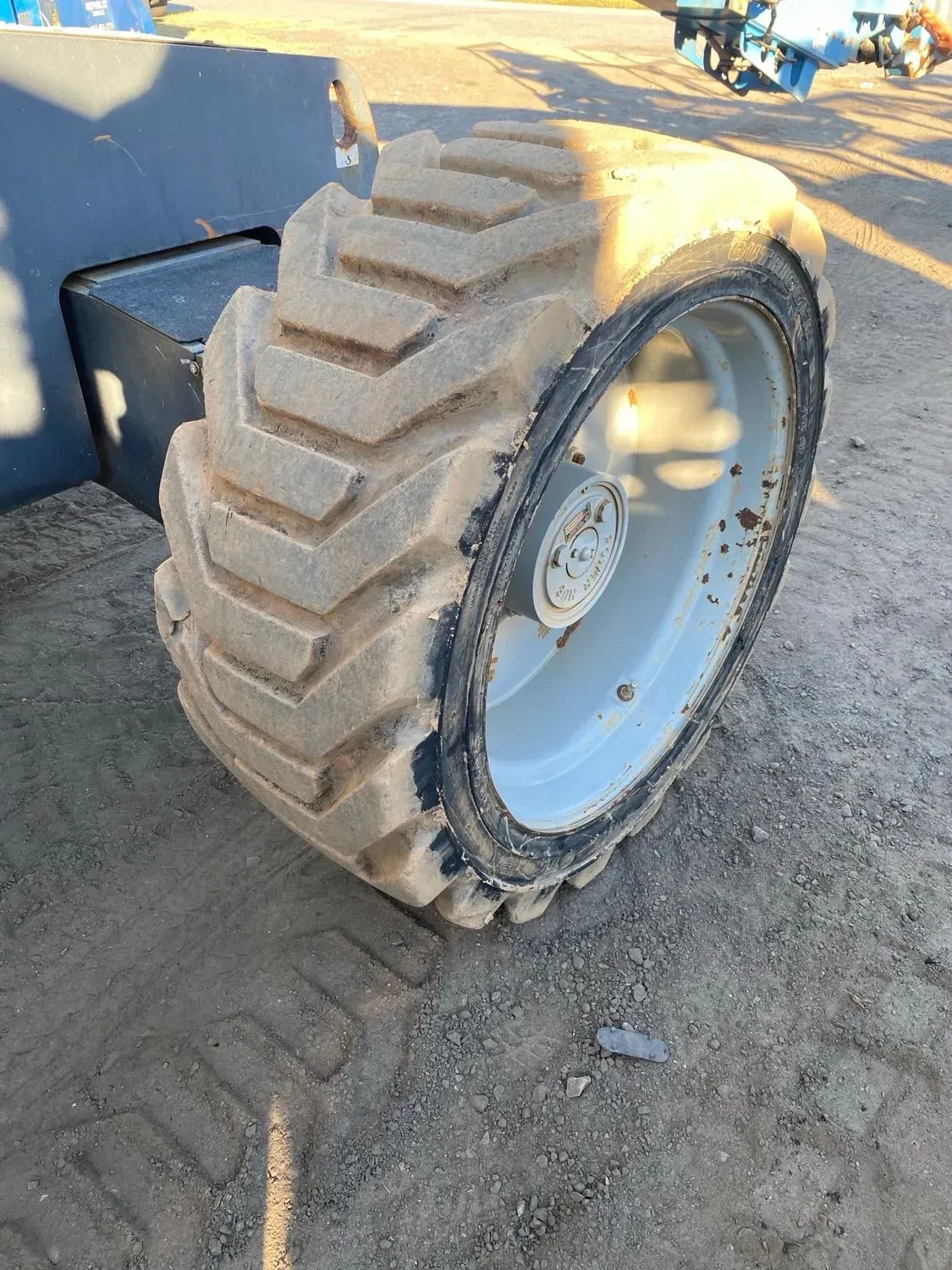 Close-up of an industrial vehicle tire with thick tread and a white wheel.