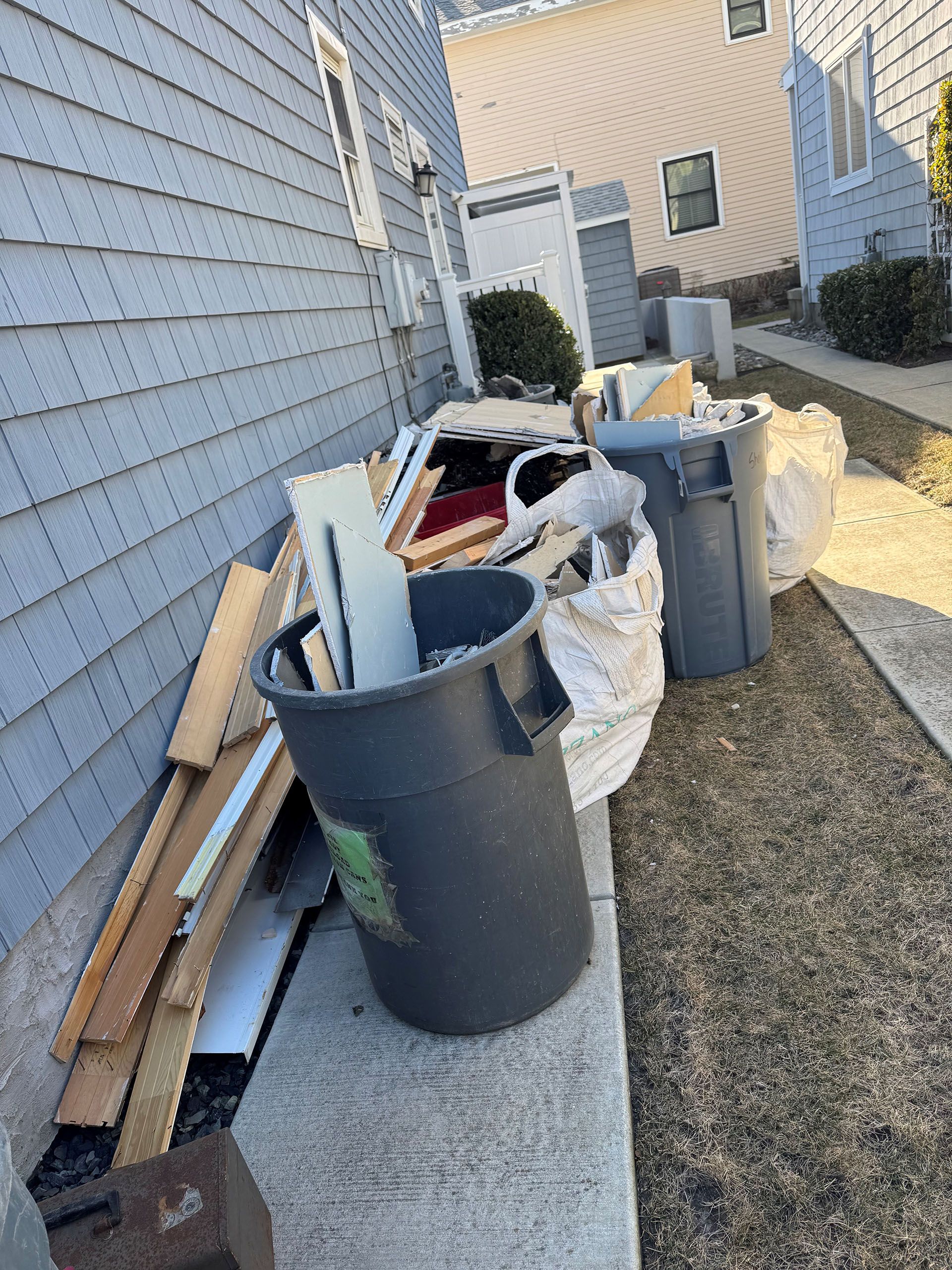 A pile of trash is sitting on the sidewalk in front of a house.