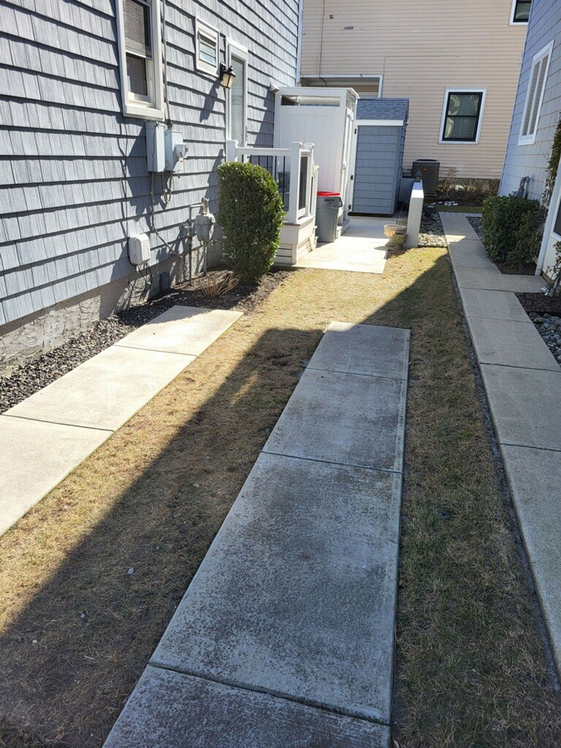 A sidewalk leading to a house with a lawn in front of it.