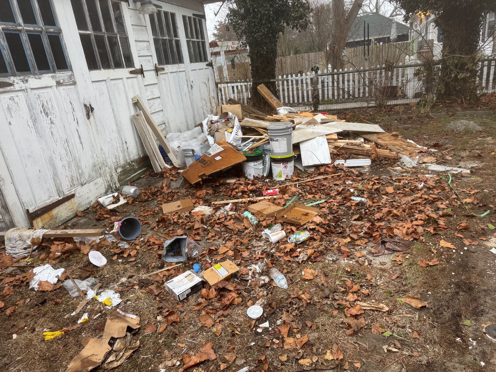 There is a lot of trash on the ground in front of a garage.