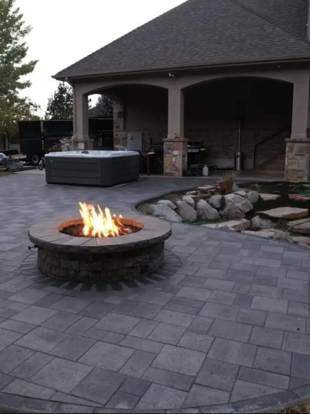 A fire pit on a patio next to a hot tub.