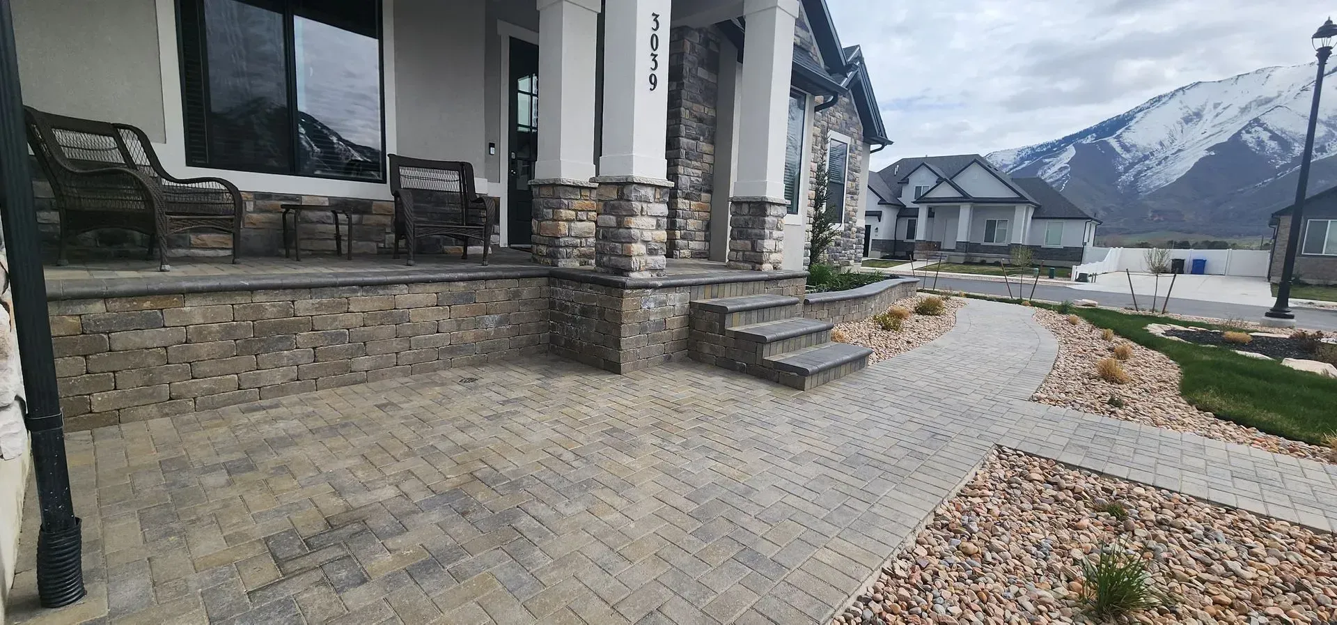 A house with a patio and stairs in front of it and mountains in the background.