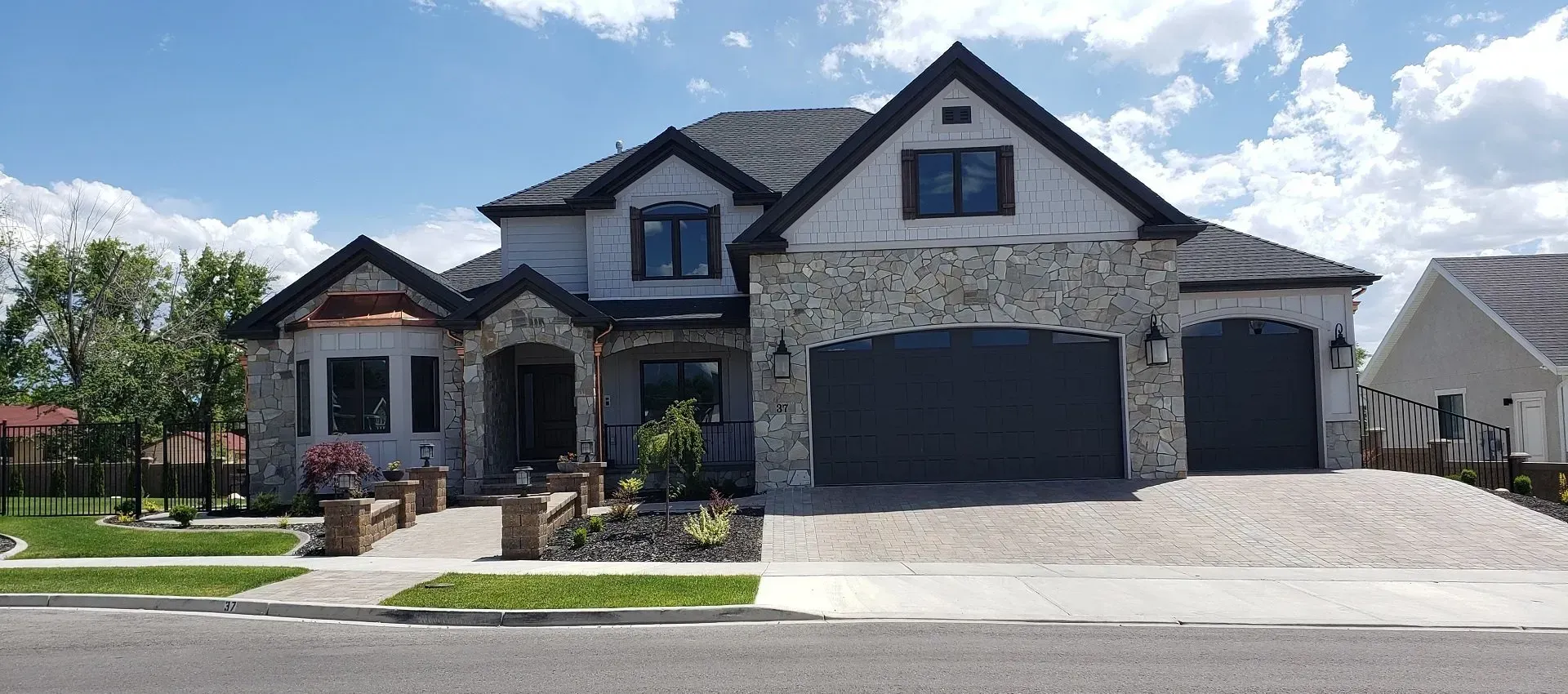 A large house with two garages is sitting on the side of the road.