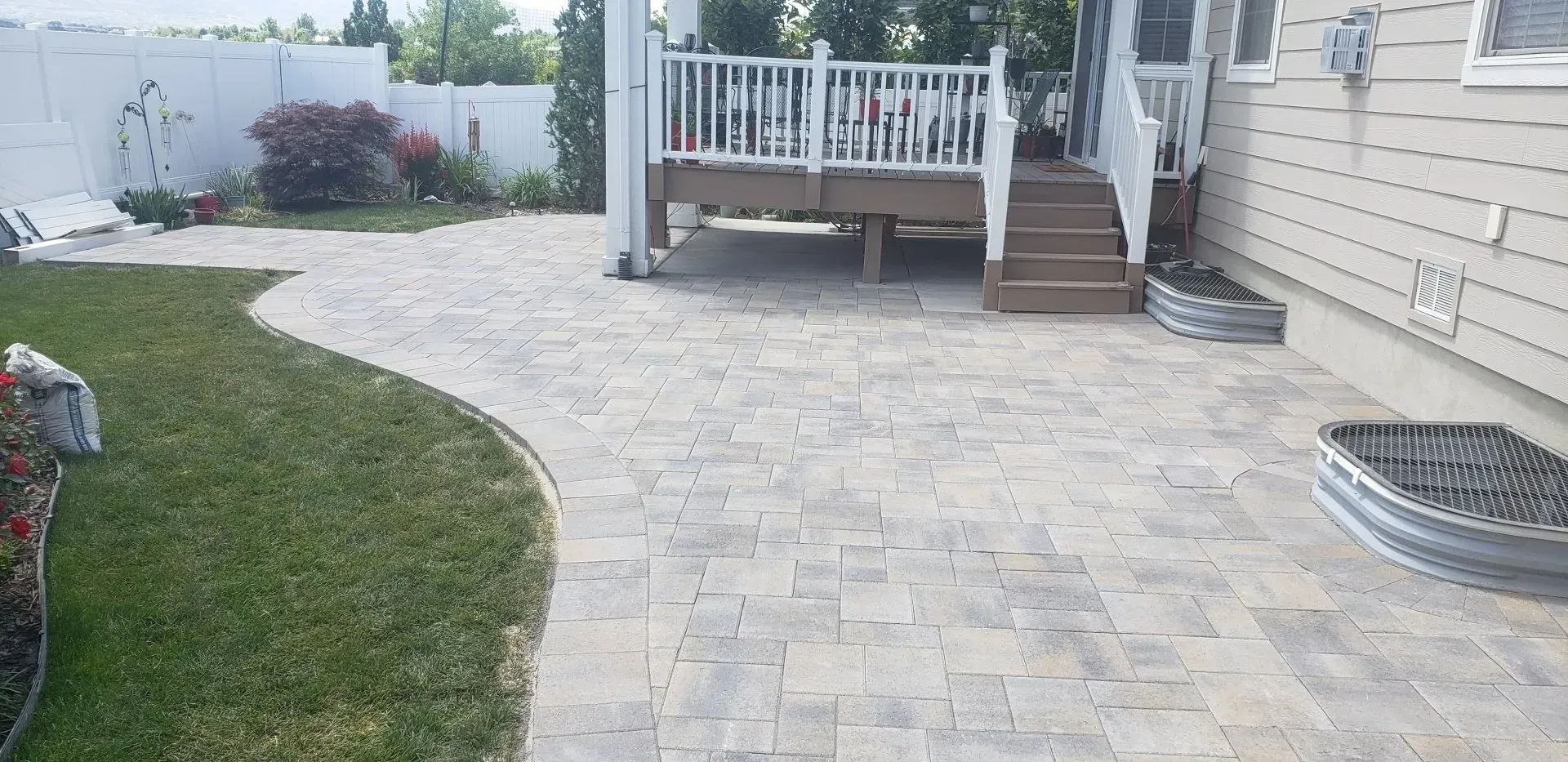 A patio with a deck and stairs in the backyard of a house.