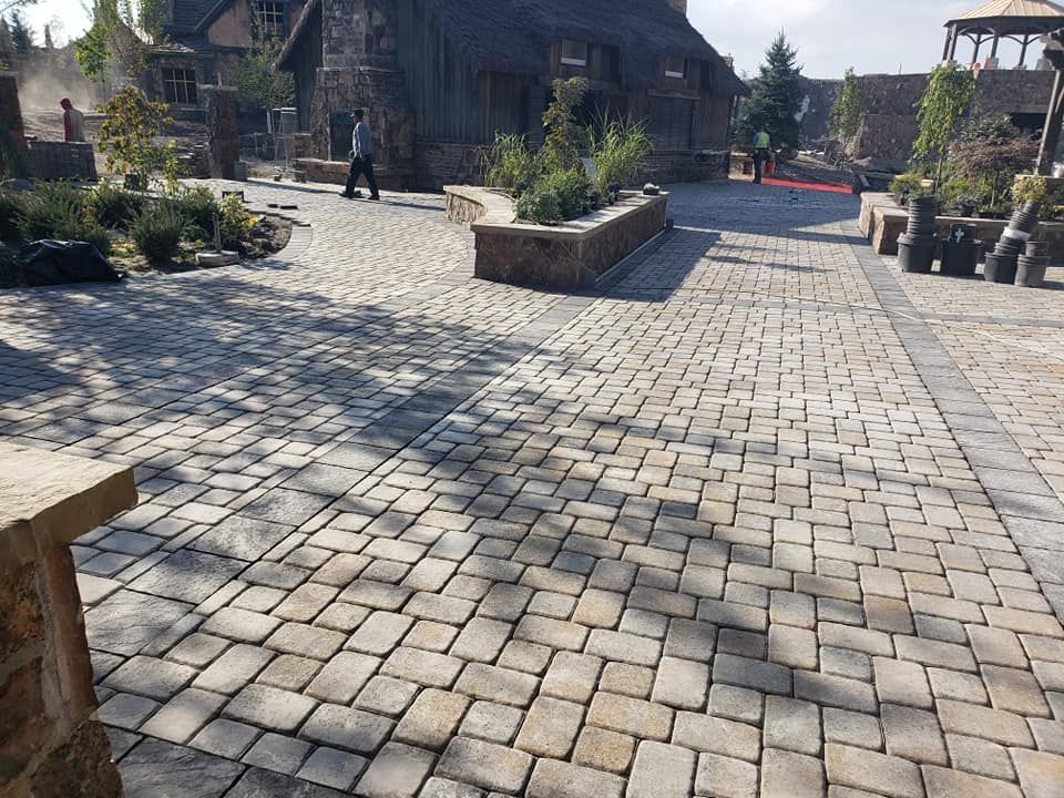 A brick walkway leading to a house with a gazebo in the background.