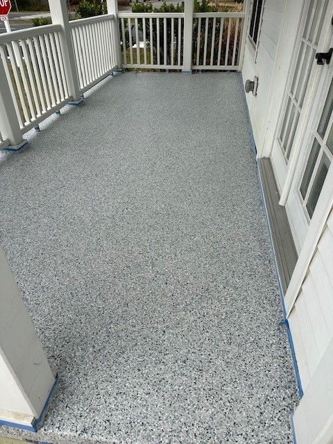 A porch with a gray concrete floor and a white railing.