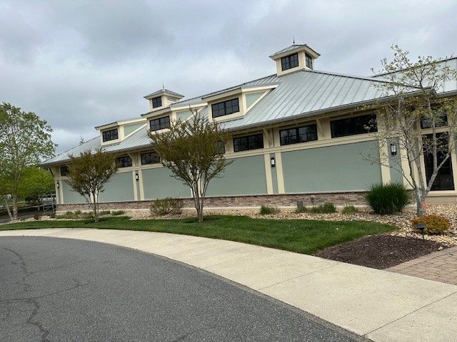 A large building with a metal roof is sitting next to a sidewalk