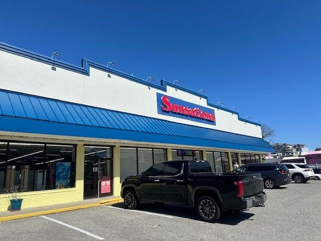 A black truck is parked in front of a store
