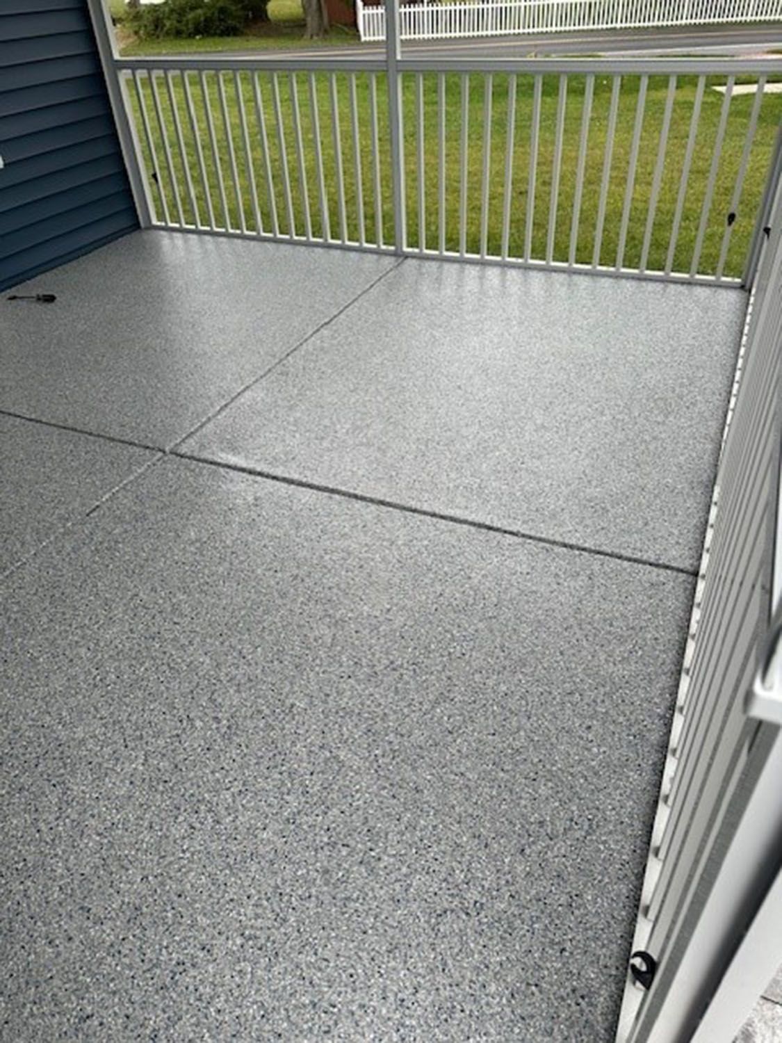 a patio with a fence and a gray concrete floor
