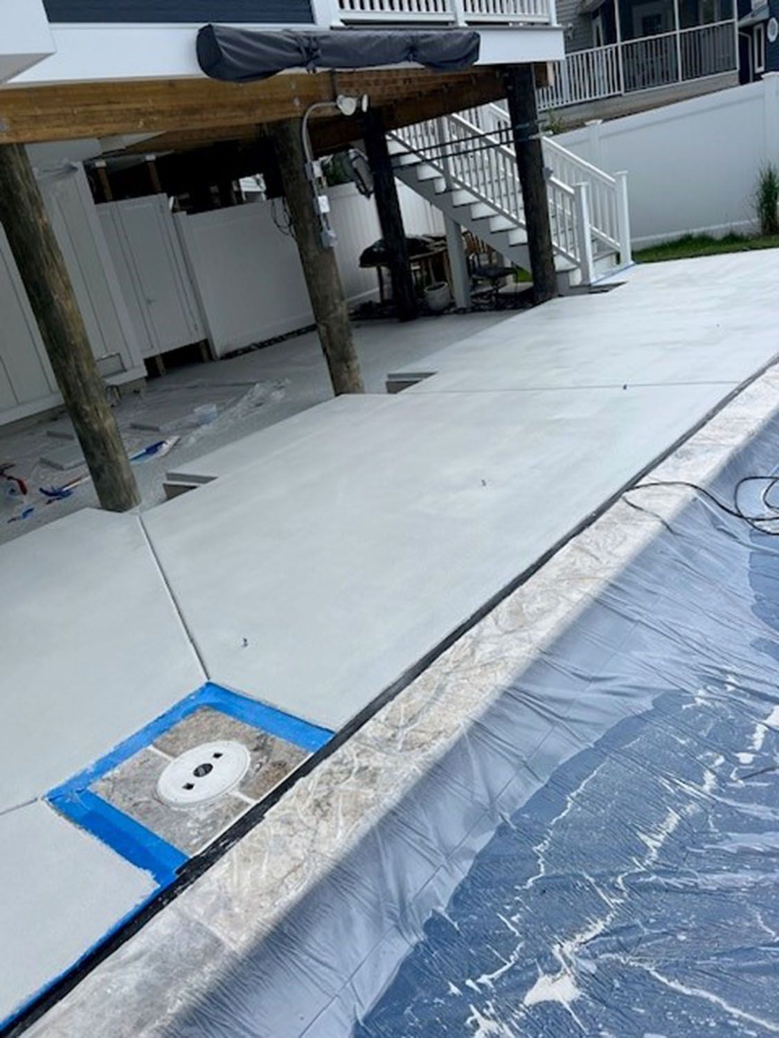 a concrete patio next to a swimming pool with a blue tape on it