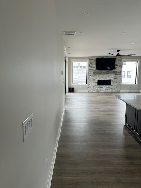 A long hallway leads to a living room with hardwood floors and a fireplace