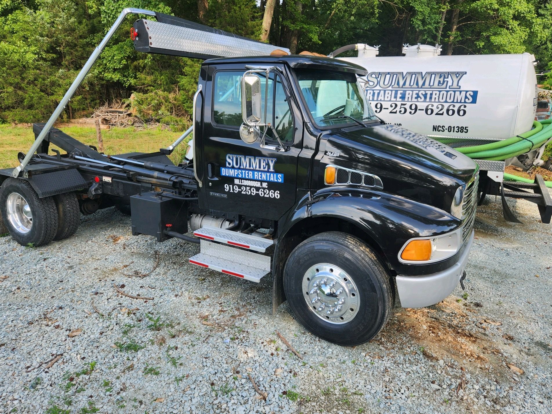 A black dump truck is parked in a gravel lot.