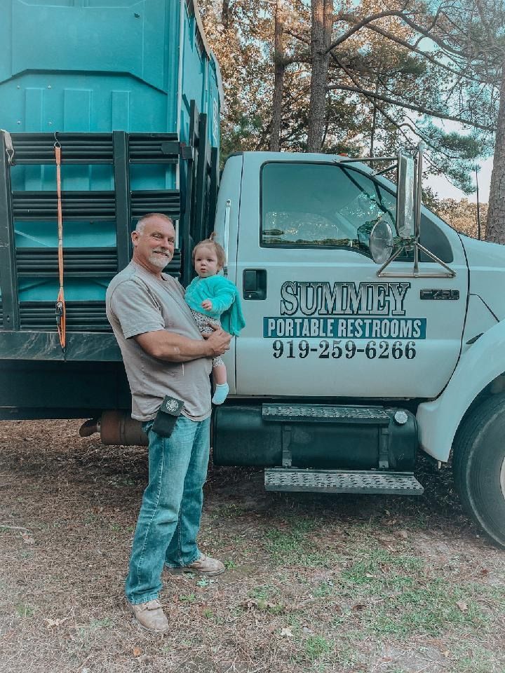 A man is holding a baby in front of a truck.