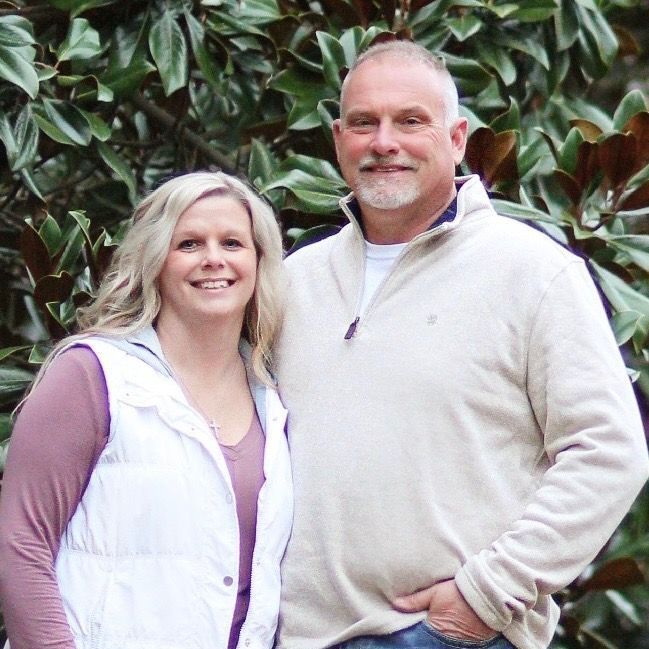 A man and a woman are posing for a picture in front of a tree.