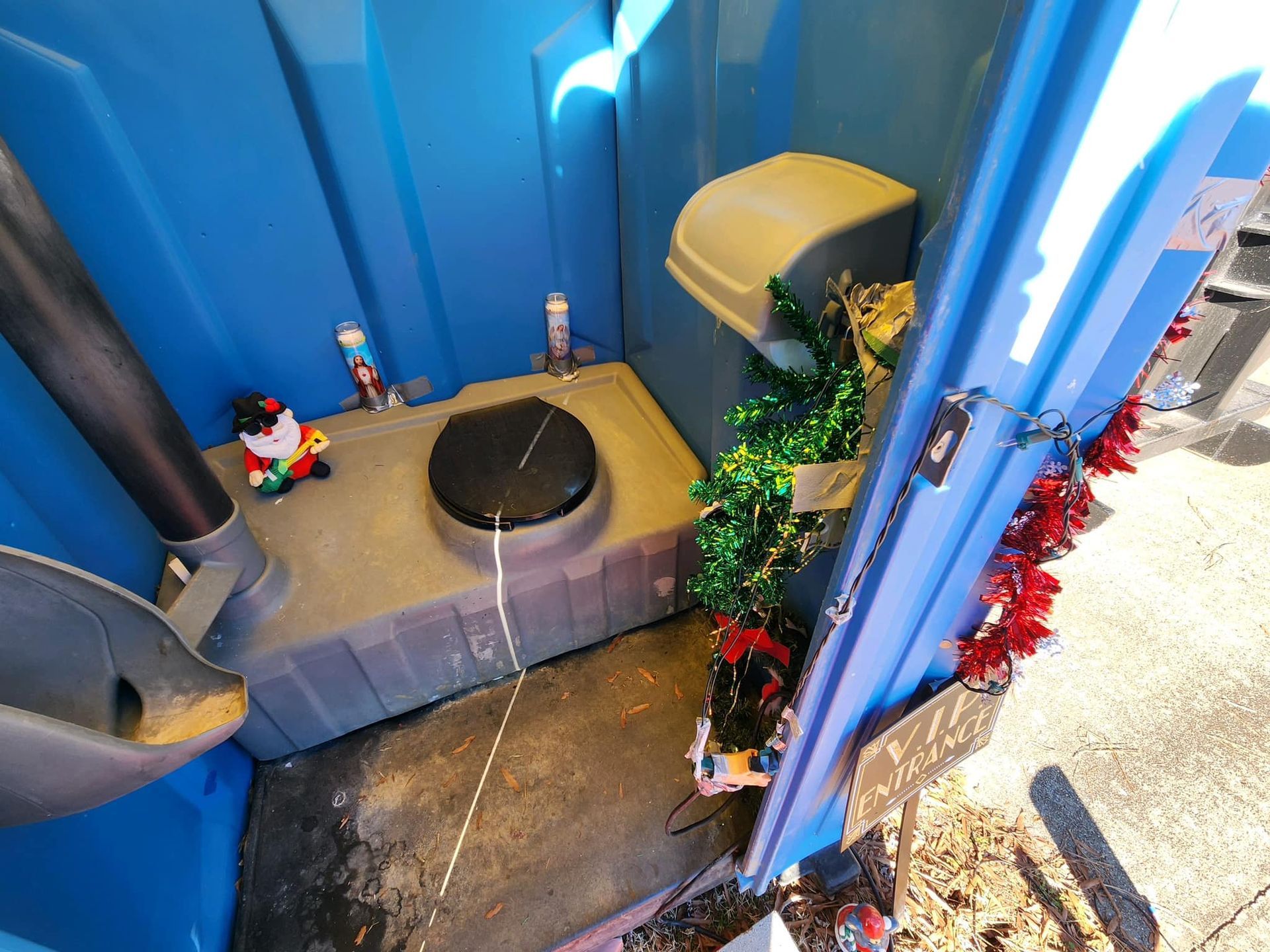 A blue portable toilet with christmas decorations on it