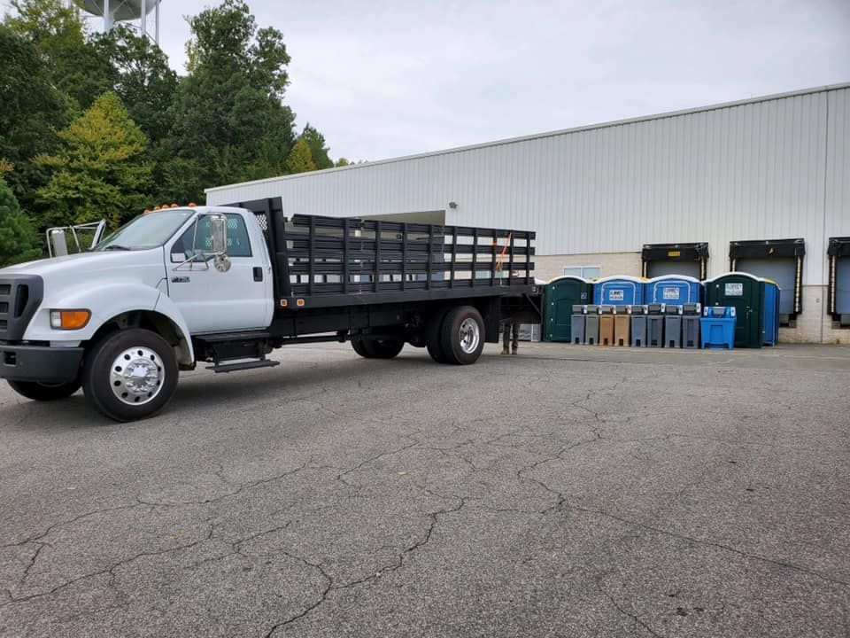 A white truck with a wooden bed is parked in front of a building.