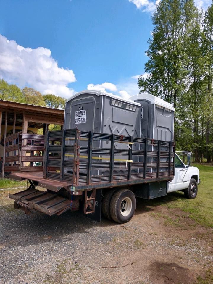 A truck with two portable toilets on the back of it.