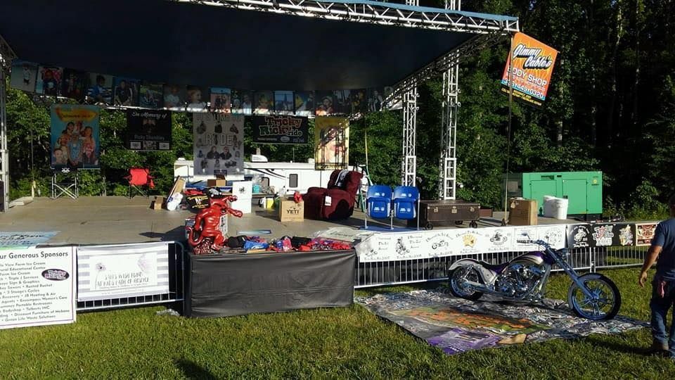 A man is standing in front of a stage with a motorcycle parked in front of it.