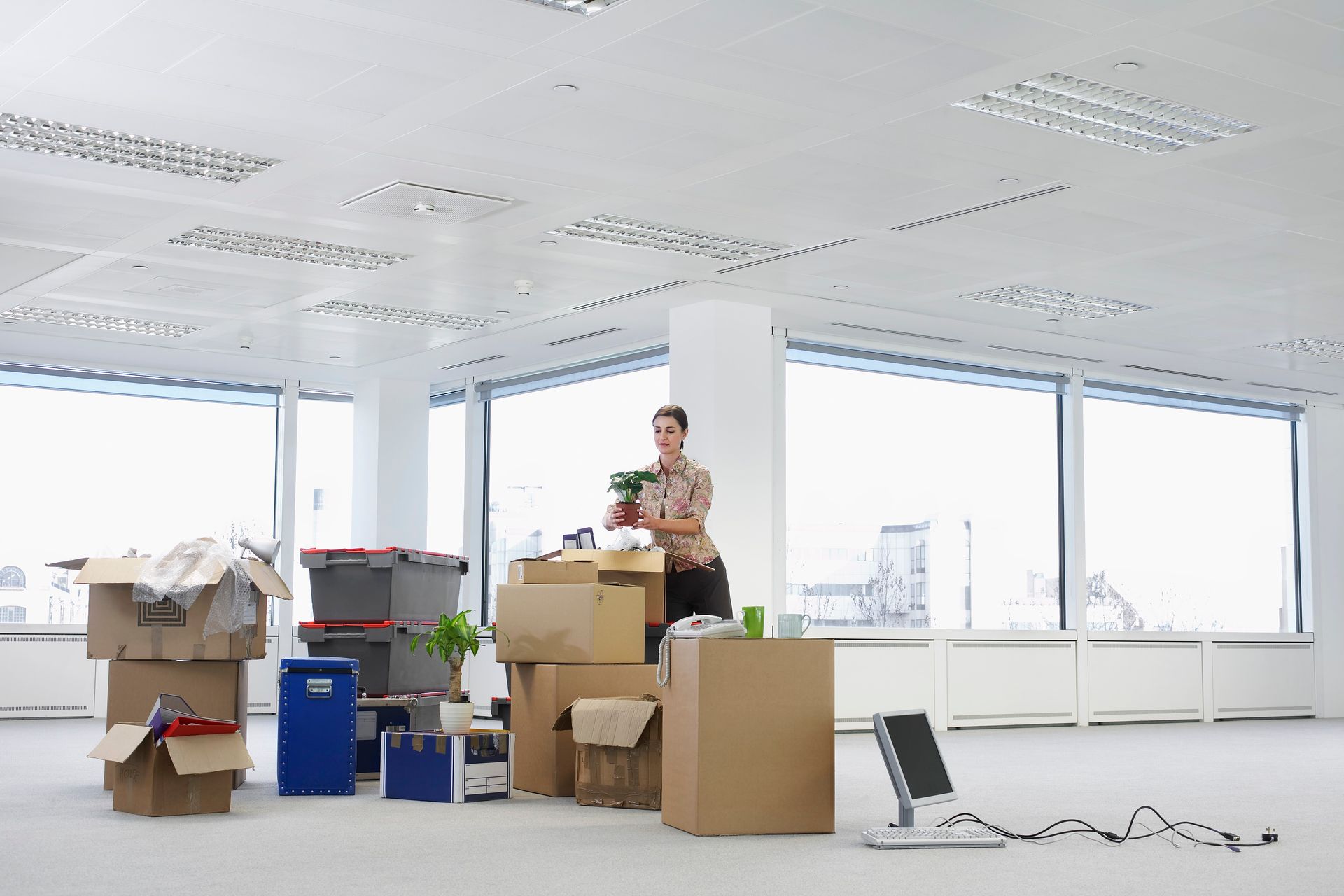 A man is standing in an empty office surrounded by boxes.