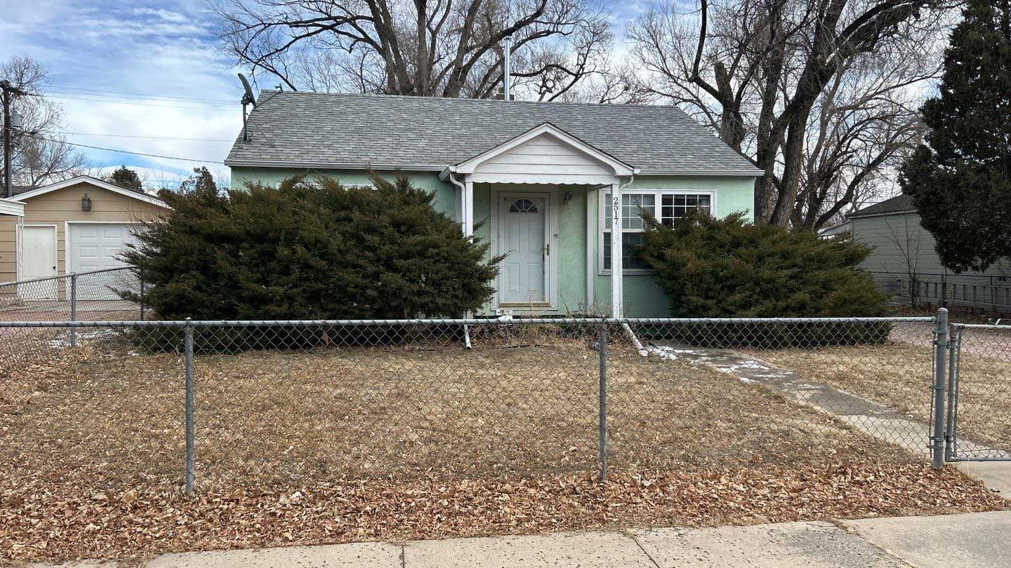 A small house with a chain link fence in front of it.