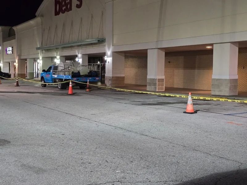 Exterior of a Bear's store at night, a blue truck parked, caution tape, and orange traffic cones.