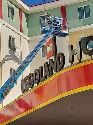Workers in a lift working on the LEGOLAND HOTEL sign.