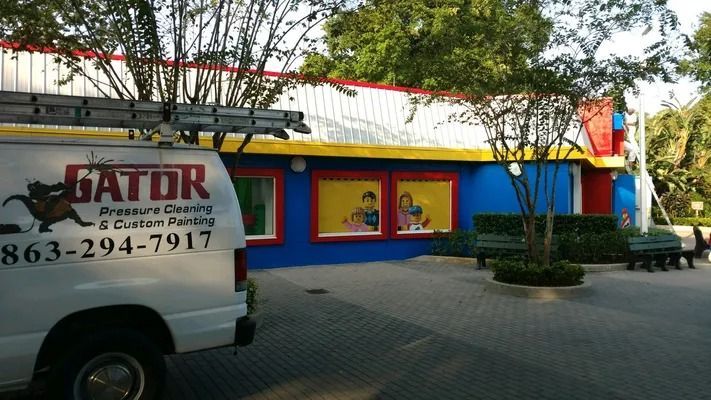 White van with Gator logo parked in front of a blue and yellow building with a red roof.