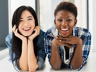 Two women are laying on a table and smiling