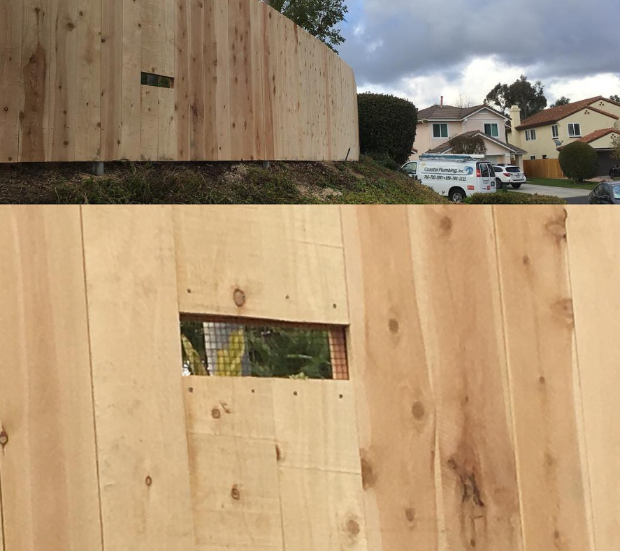 A wooden fence with a hole in the middle of it