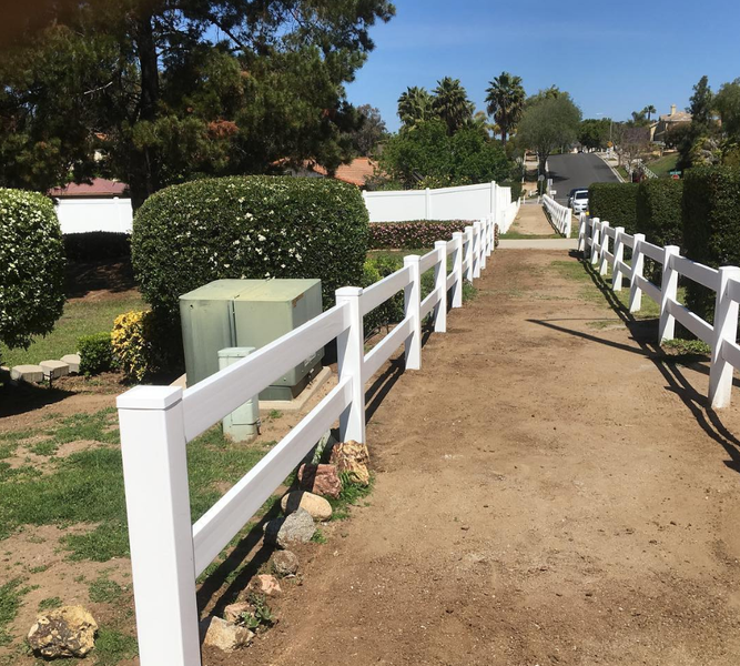 A white fence along the side of a dirt road