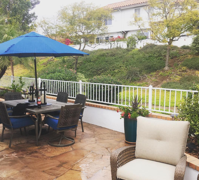 A patio with a table and chairs under an umbrella