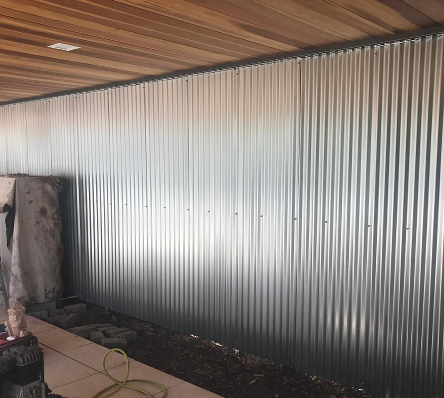 A room with a metal wall and a wooden ceiling.