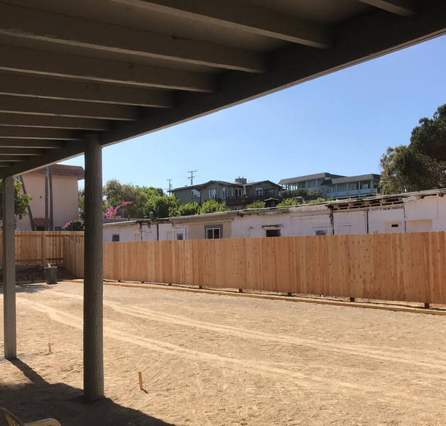A wooden fence is surrounding a dirt field
