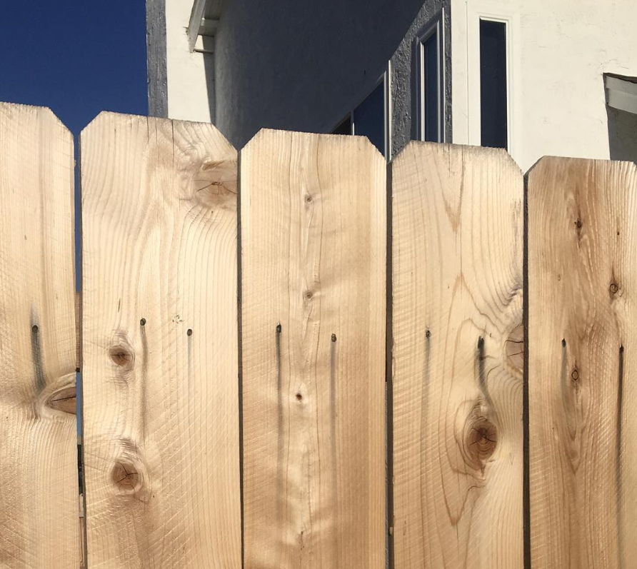 A wooden fence is sitting in front of a white house.