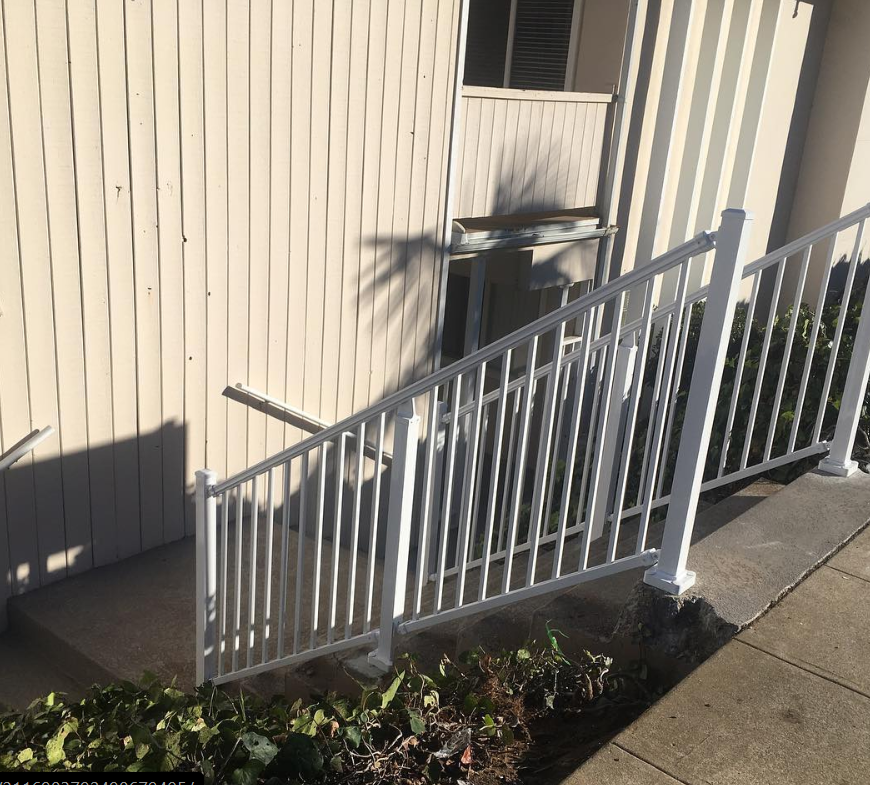 A white railing with stairs leading up to a building