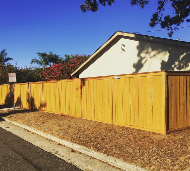 A wooden fence surrounds a house with a no parking sign in front of it