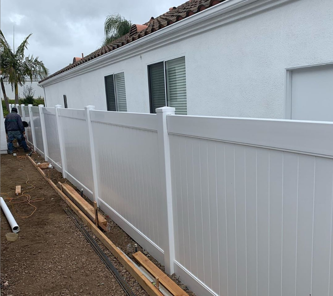 A white fence is being built in front of a white house