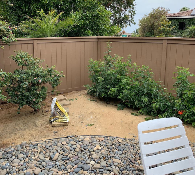 A white chair is sitting in front of a wooden fence