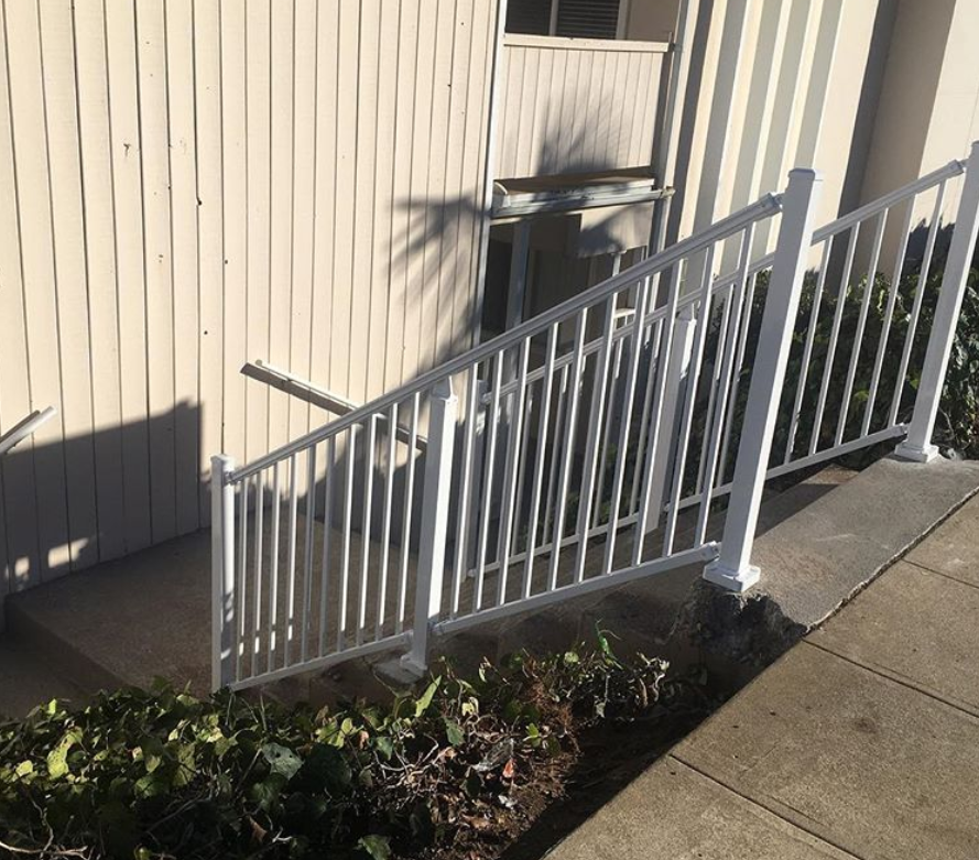 A white railing with stairs leading up to a building