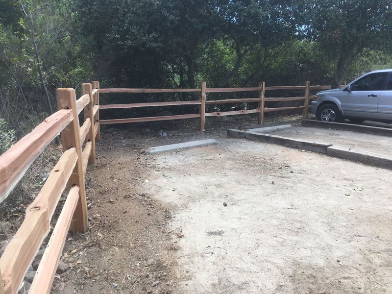 A car is parked in a parking lot next to a wooden fence.