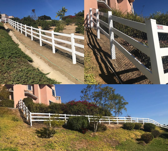 A white fence surrounds a house on a hillside
