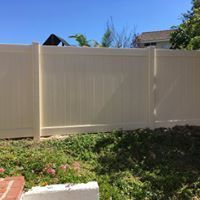 A white vinyl fence is sitting in the middle of a lush green yard.