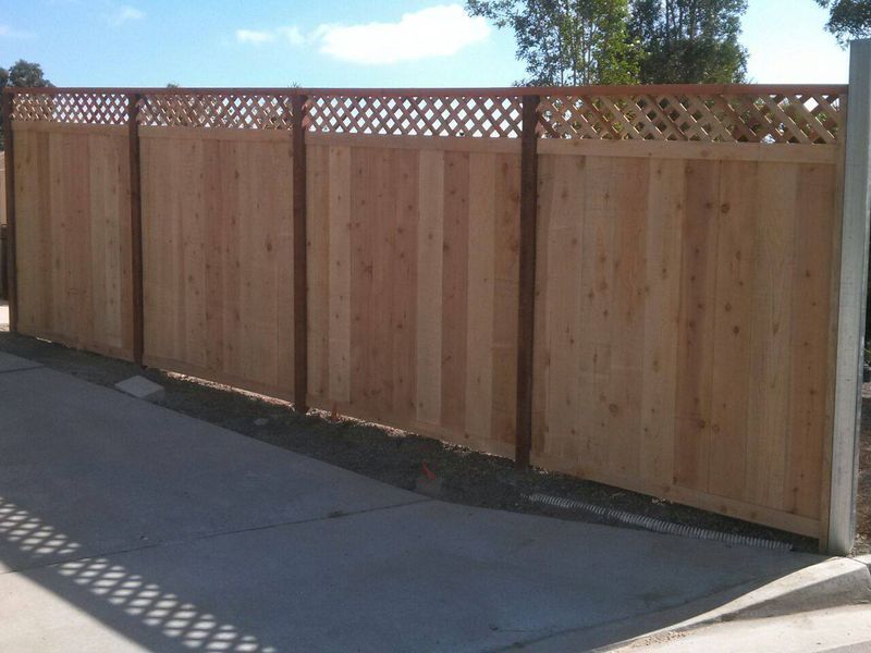 A wooden fence is sitting on the side of a road