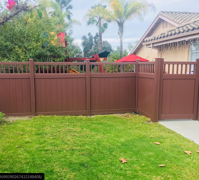 A brown wooden fence is in the backyard of a house.