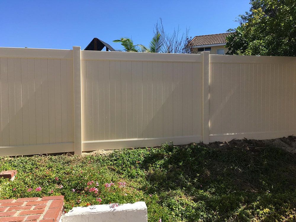 A white fence is surrounding a lush green yard.