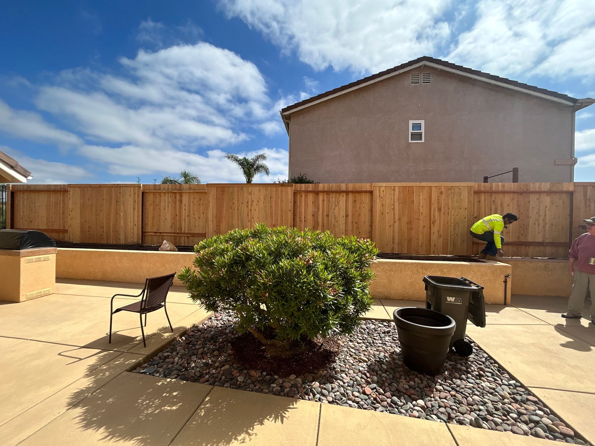 A man is working on a wooden fence in front of a house.