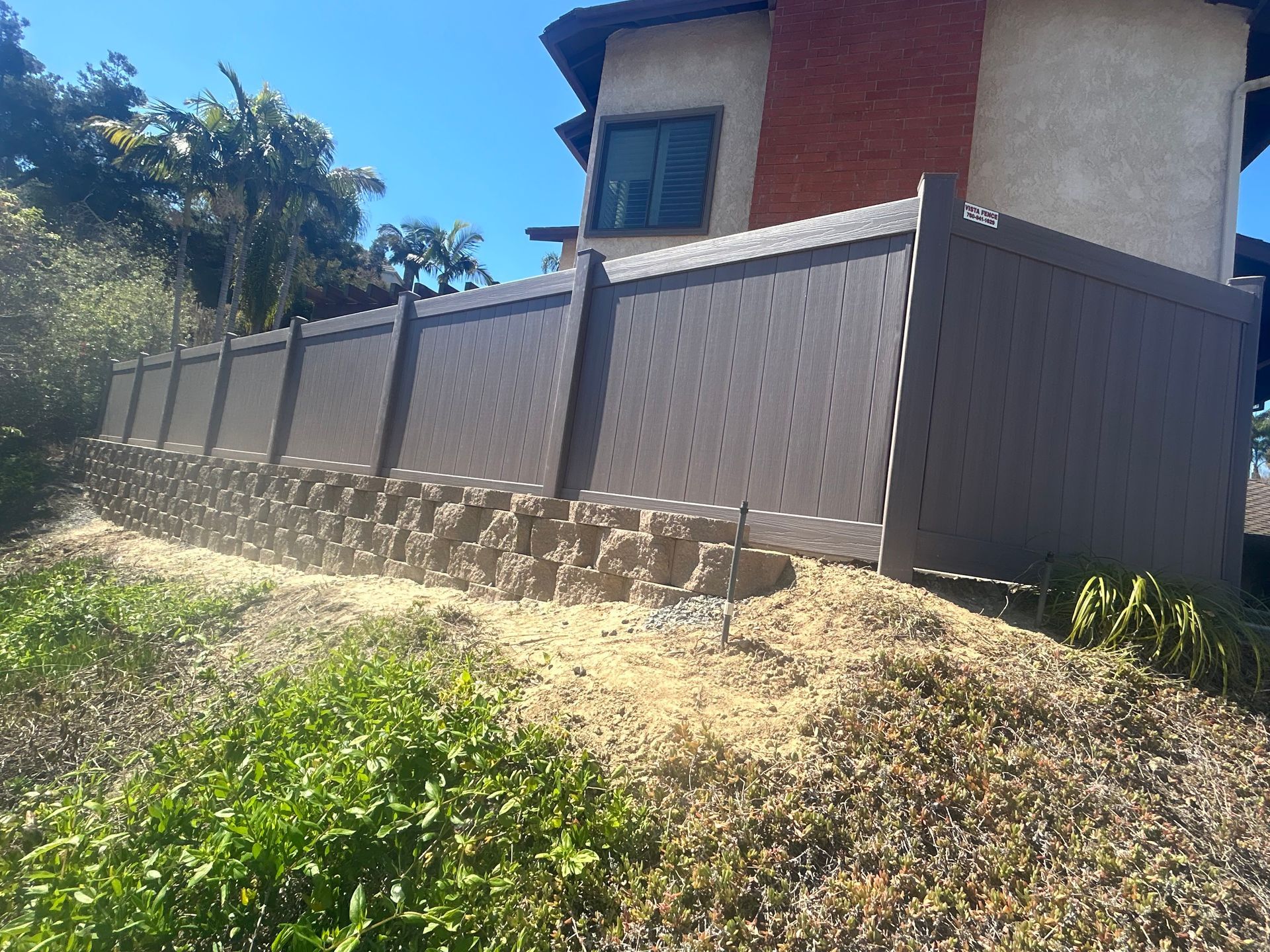 A house with a stone wall and a fence in front of it.
